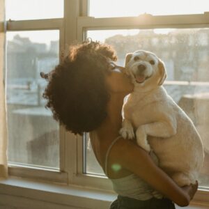 Black woman kissing cute purebred dog