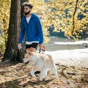 African American male walking with dog in park