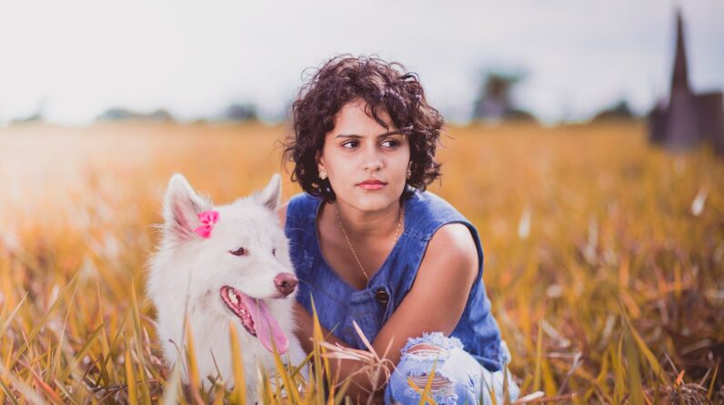 Woman Squatting Near White Dog on Grass Field
