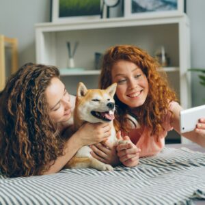two women laying on a bed with a dog
