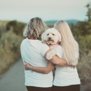woman in blue t-shirt hugging white dog