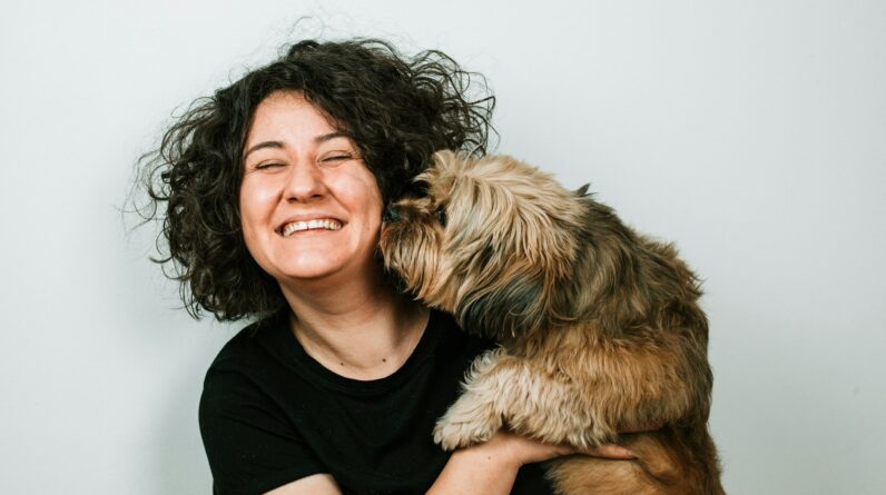 dog kissing woman in black crew-neck shirt