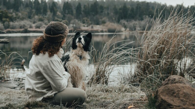 a woman sitting on the ground next to a dog