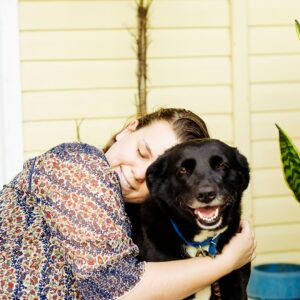 woman hugging black dog